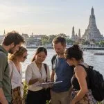 Four travellers planning a private Bangkok day trip with a Thai travel professional near Wat Arun