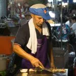 Street-food cook preparing a meal at a market in Thailand