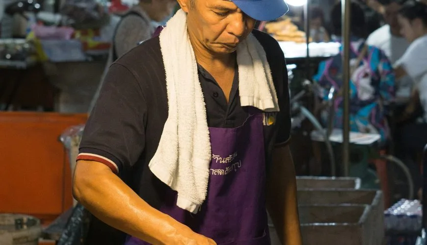 Street-food cook preparing a meal at a market in Thailand