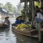 Floating market vendors selling fruit from wooden boats on a canal near Bangkok