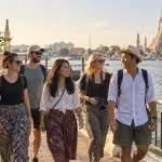 A private group of six adults walking beside the Chao Phraya River with Wat Arun in view