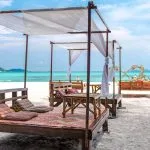 Beach seating beside turquoise water on Koh Lipe