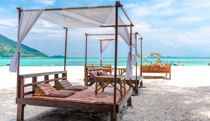 Beach seating beside turquoise water on Koh Lipe