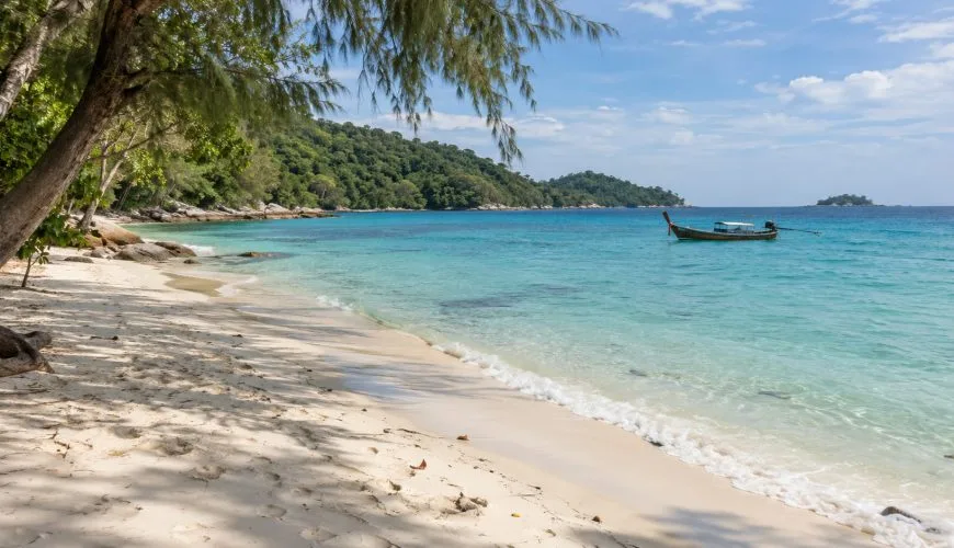 Quiet white-sand beach on Ko Samet with clear water and a Thai long-tail boat offshore