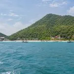 View of Koh Larn from the sea with forested hills, beach and boats