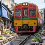 Passenger train passing safely through Maeklong Railway Market
