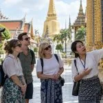 A Thai guide explaining temple details to a closed group of travellers in Bangkok