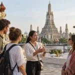 A Thai private guide speaking with four travellers near Wat Arun in Bangkok