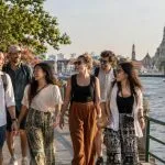 A private group of six adults walking beside the Chao Phraya River with Wat Arun in view